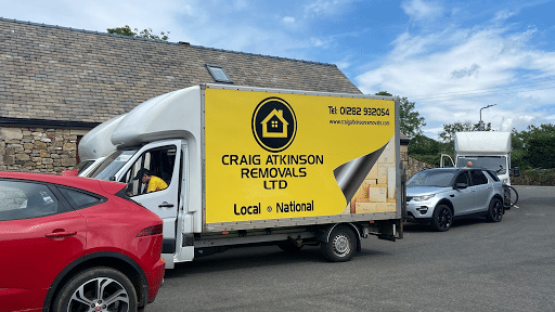 Two Craig Atkinson Removals vans parked outside a stone building during a moving job.