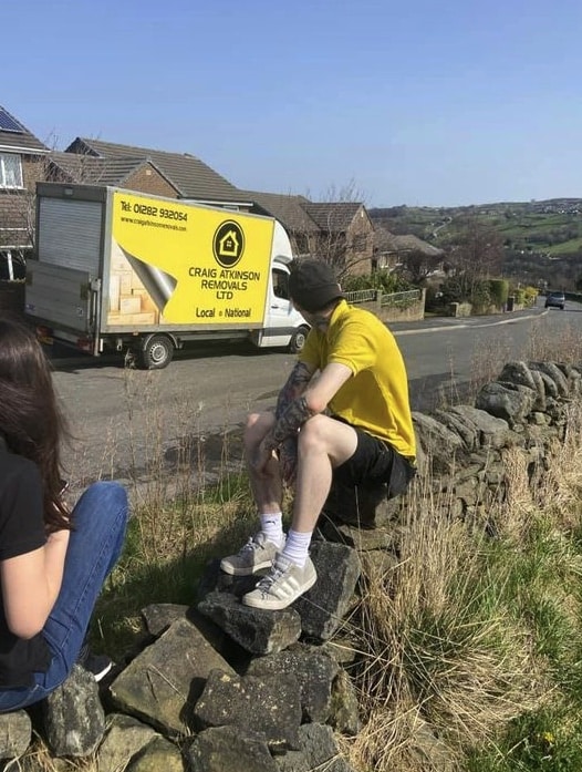 Craig Atkinson Removals van parked on a hillside road with team members taking a break in the sunshine.