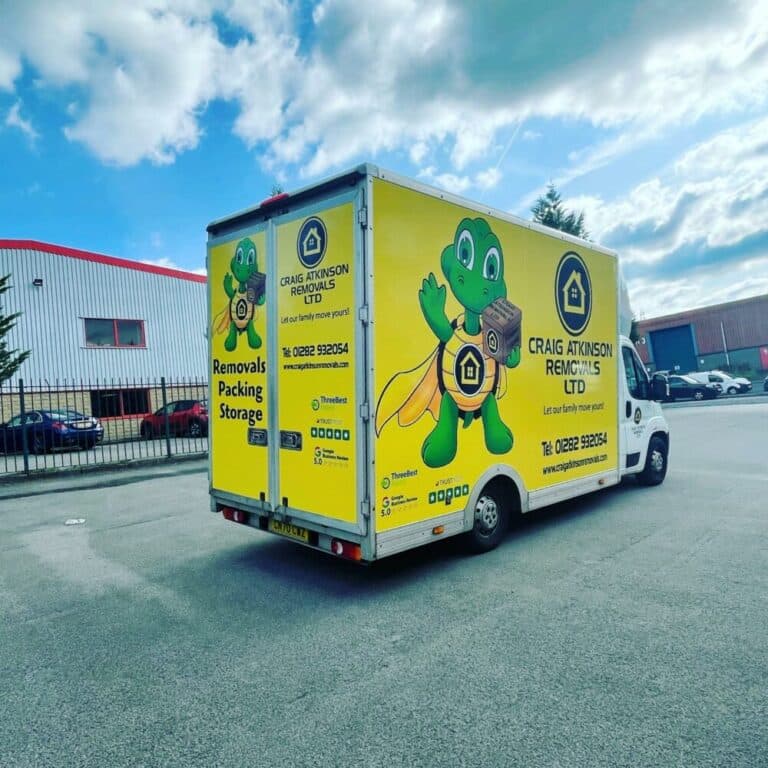 Craig Atkinson Removals yellow van with company mascot parked outside an industrial estate.