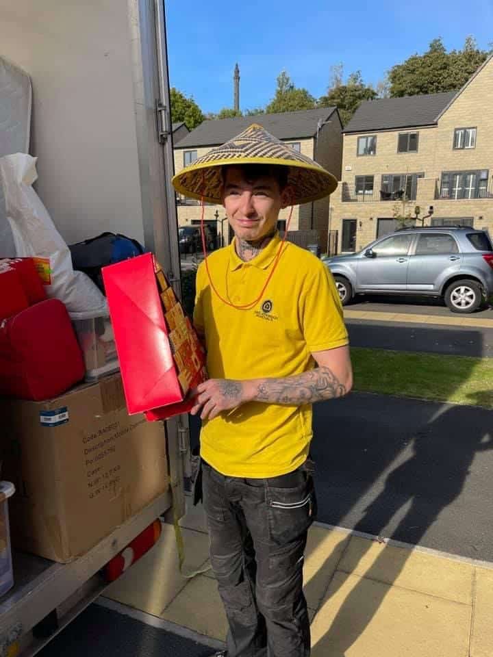 Craig Atkinson Removals team member smiling while loading boxes into the removals van on a sunny moving day in Lancashire.