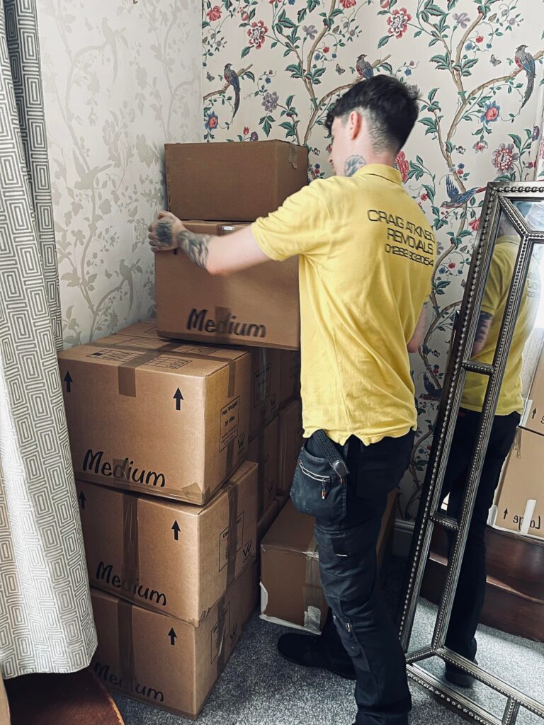 Craig Atkinson Removals team member stacking labelled moving boxes carefully during a home removal.