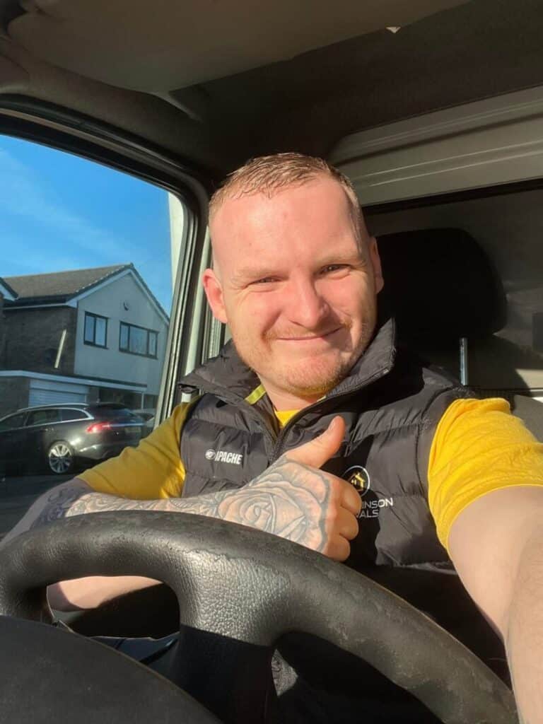 Craig Atkinson Removals team member smiling and giving a thumbs-up while sitting in a removals van.