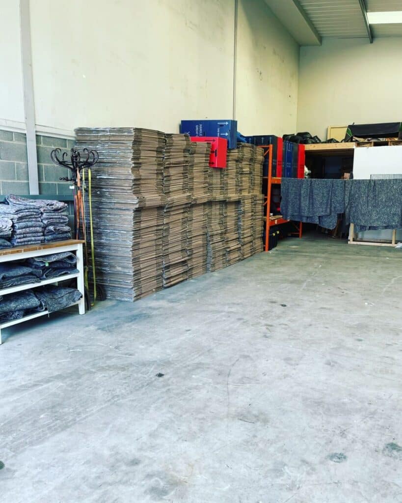 Neatly stacked cardboard boxes and removal blankets inside Craig Atkinson Removals warehouse.