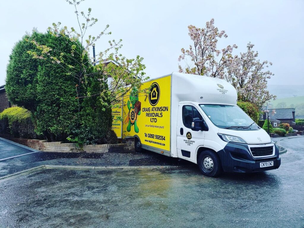 Craig Atkinson Removals van parked outside a residential home in Bolton on a rainy moving day.
