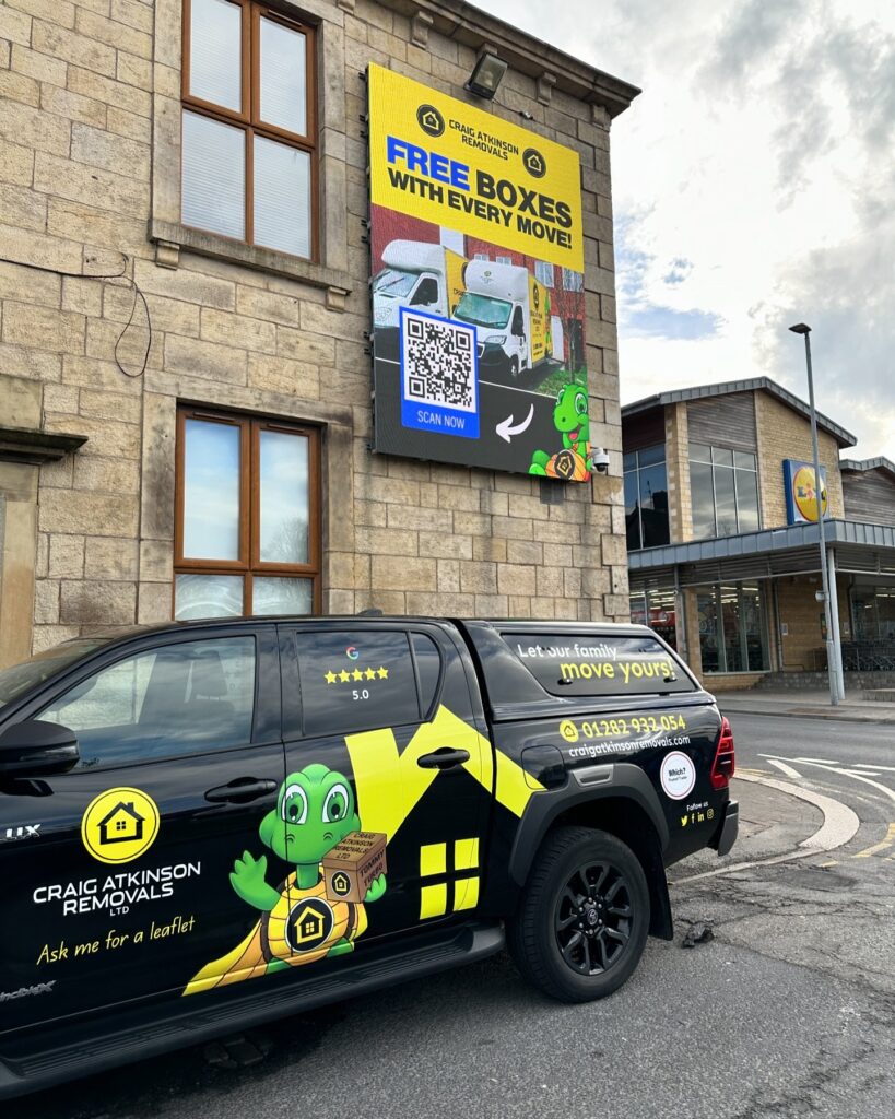 Craig Atkinson Removals vehicle parked beneath a large billboard in Burnley advertising free boxes with every move.