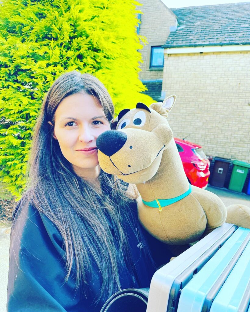 Woman smiling while holding a plush Scooby-Doo toy outdoors, celebrating International Women’s Day.