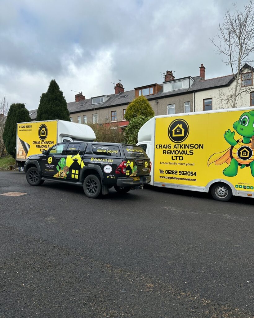 Branded Craig Atkinson Removals vans and pickup truck parked on a Lancashire street, ready for a move.