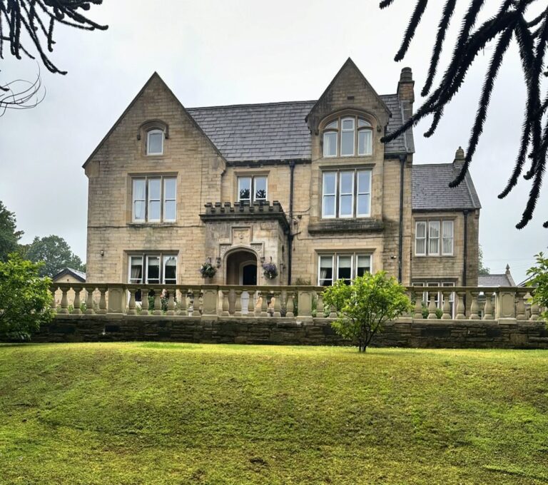 A grand stone mansion in Barrowford, Lancashire, surrounded by greenery, relocated by Craig Atkinson Removals.