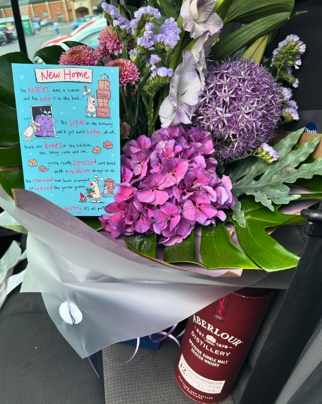 A bouquet of flowers, a bottle of Aberlour whisky, and a “New Home” card gifted by Craig Atkinson Removals to a customer.