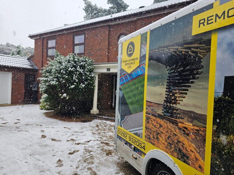 Craig Atkinson Removals van outside a large red-brick house during snowy weather, completing a long-distance house move.