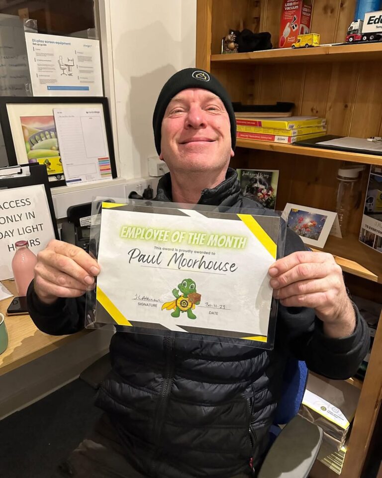 Craig Atkinson Removals team member Paul Moorhouse smiling and holding his Employee of the Month certificate.