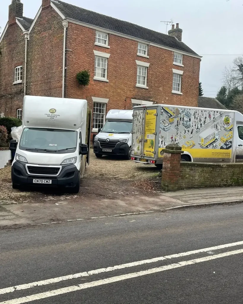 Craig Atkinson Removals vans parked outside a large brick home in Clitheroe during a professional house move.