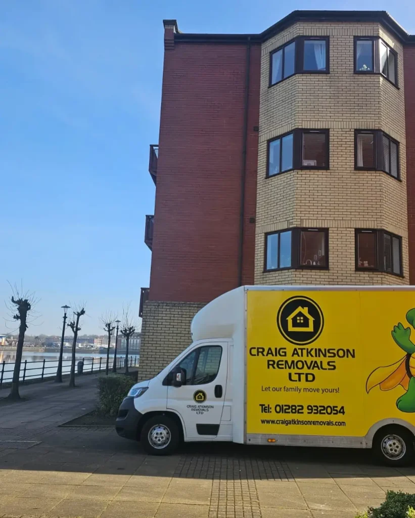 Craig Atkinson Removals van parked outside modern waterfront apartments at Salford Quays, Manchester.