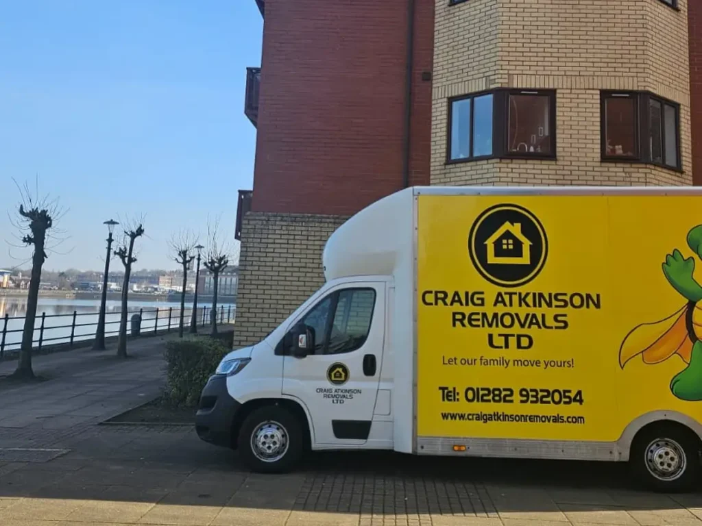 Craig Atkinson Removals van parked outside modern waterfront apartments at Salford Quays, Manchester.