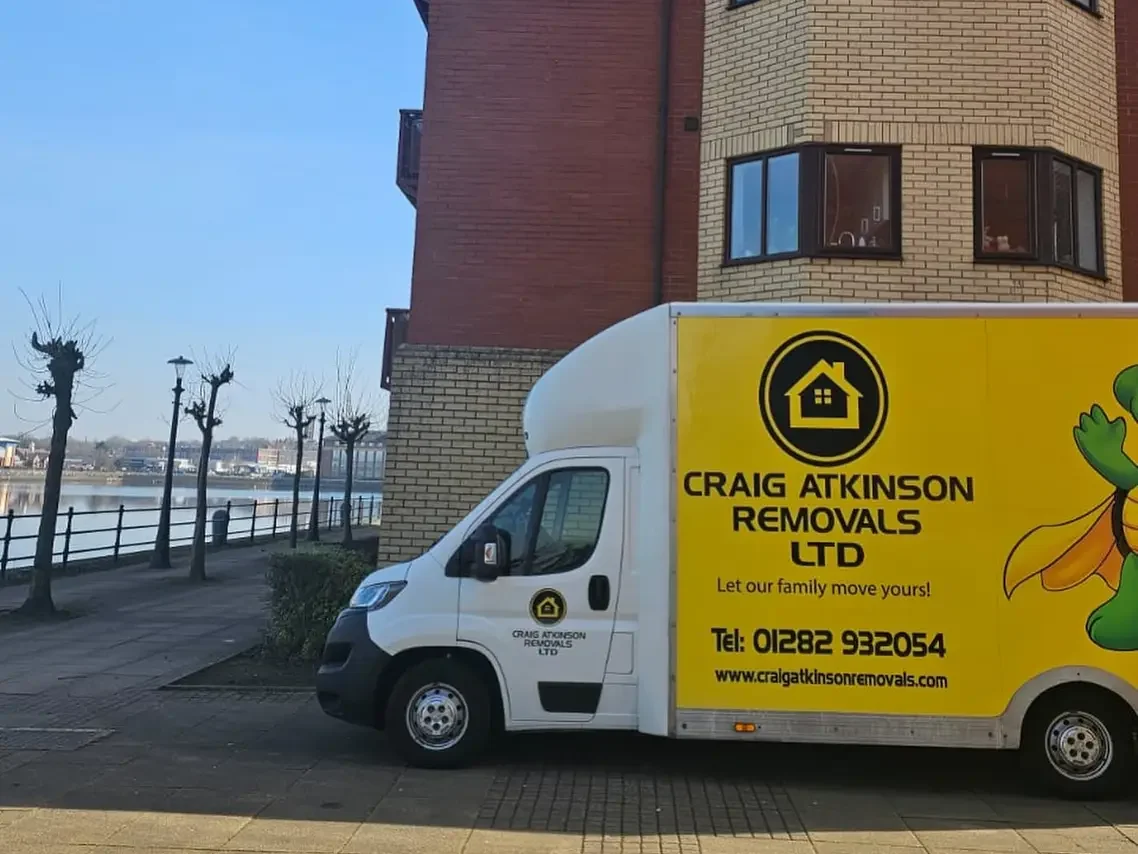 Craig Atkinson Removals van parked outside modern waterfront apartments at Salford Quays, Manchester.