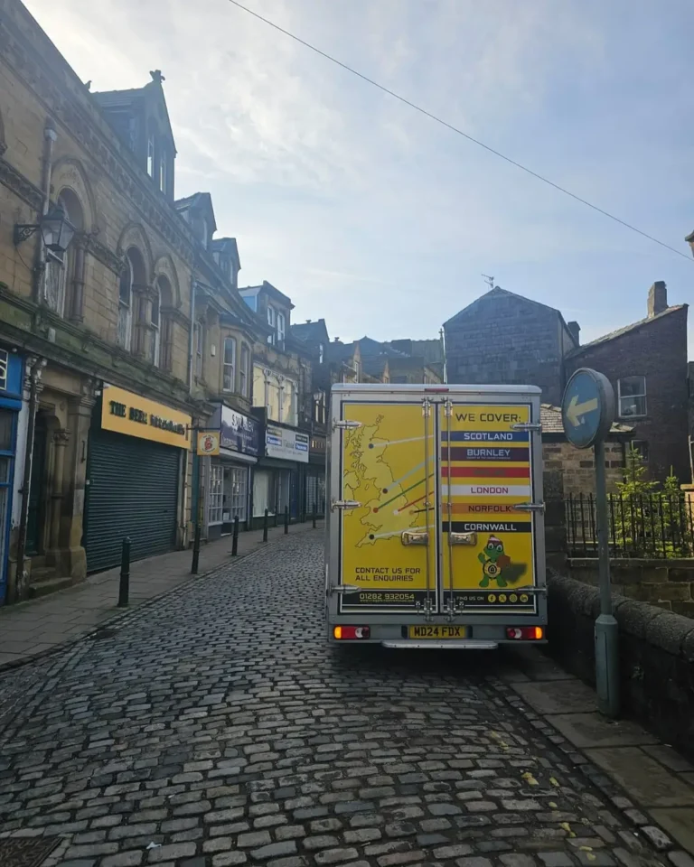 Craig Atkinson Removals van parked on a cobbled street in Burnley, showing company coverage map on the back doors.