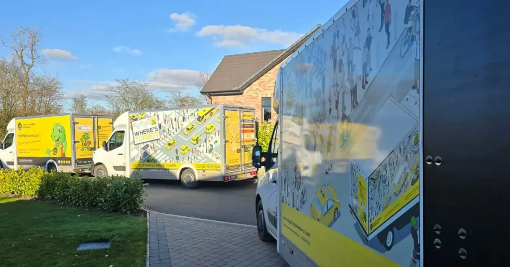 Craig Atkinson Removals vans lined up on a residential street, featuring the yellow Tommy Turbo and Where’s Turbo designs.