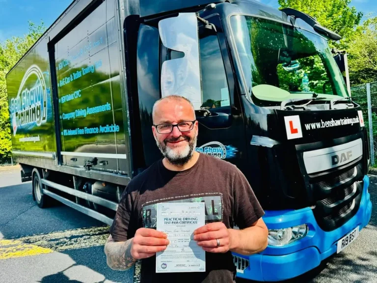 Steve from Craig Atkinson Removals proudly holding his HGV Class 2 practical driving test certificate in front of a Ben Shaw Training lorry.