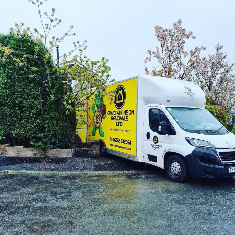 Craig Atkinson Removals van parked outside a residential home in Bolton on a rainy moving day.
