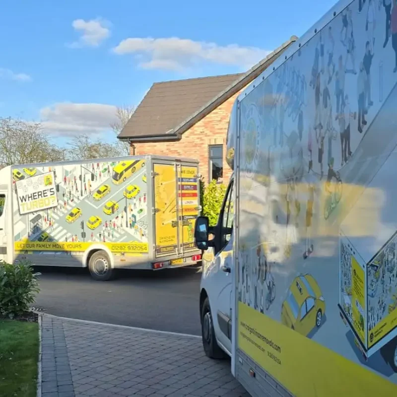 Craig Atkinson Removals vans lined up on a residential street, featuring the yellow Tommy Turbo and Where’s Turbo designs.
