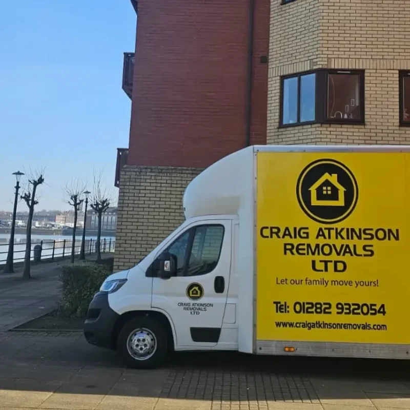 Craig Atkinson Removals van parked outside modern waterfront apartments at Salford Quays, Manchester.